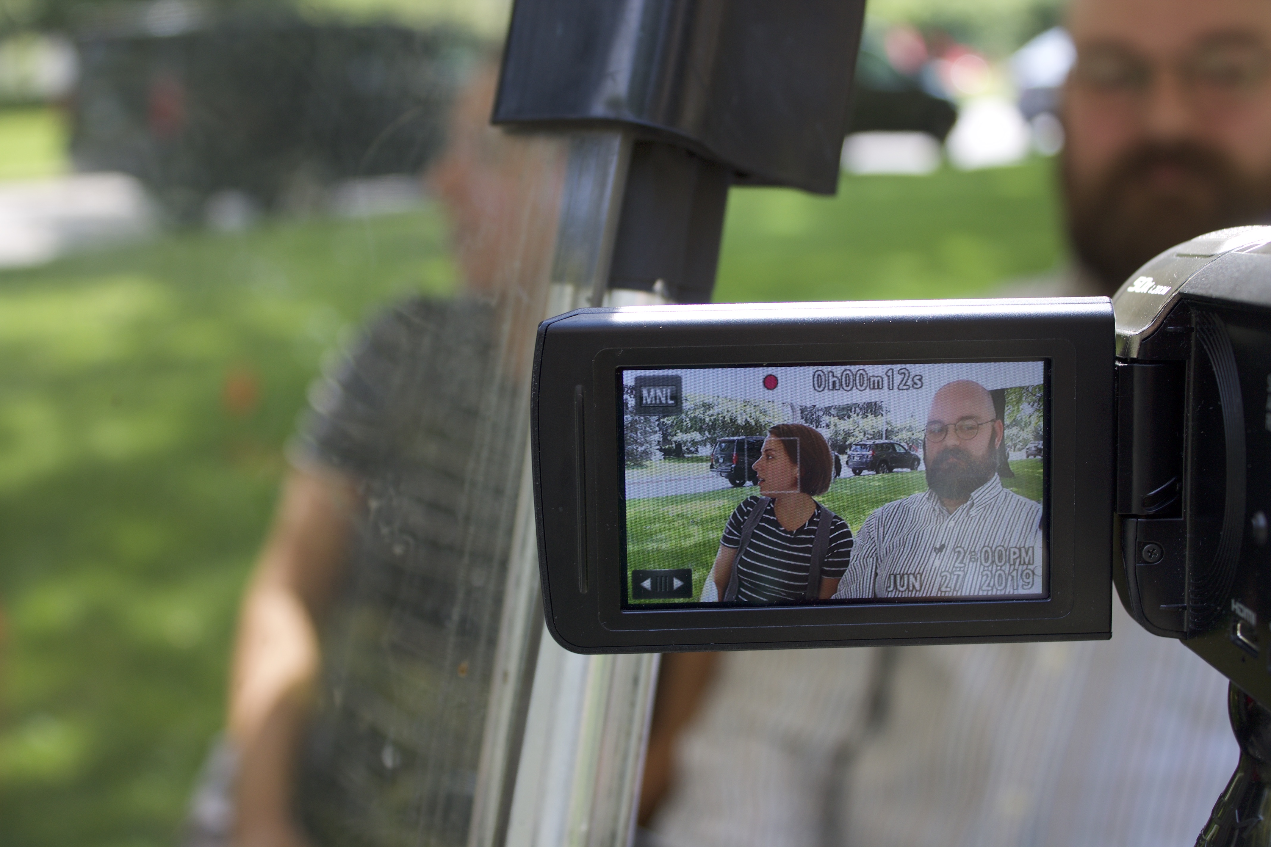 Image for Episode filming in progress: while Jess and Tony converse in a moving golf cart, members of the production team capture the filming underway in the camera